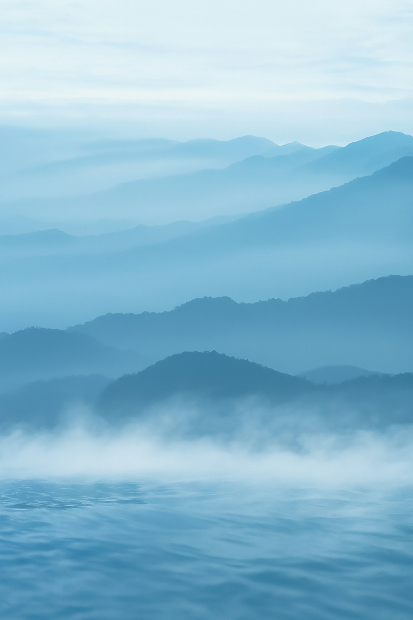 Layers of misty blue mountain ridges above still water